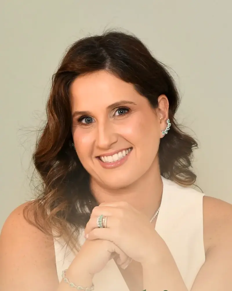 Dra. Júlia sorrindo, com as mãos sob o queixo